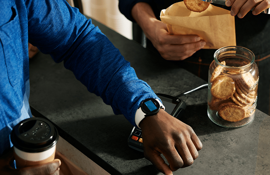 An employee makes a contactless payment using Google Pay via a Wear OS smartwatch at the till